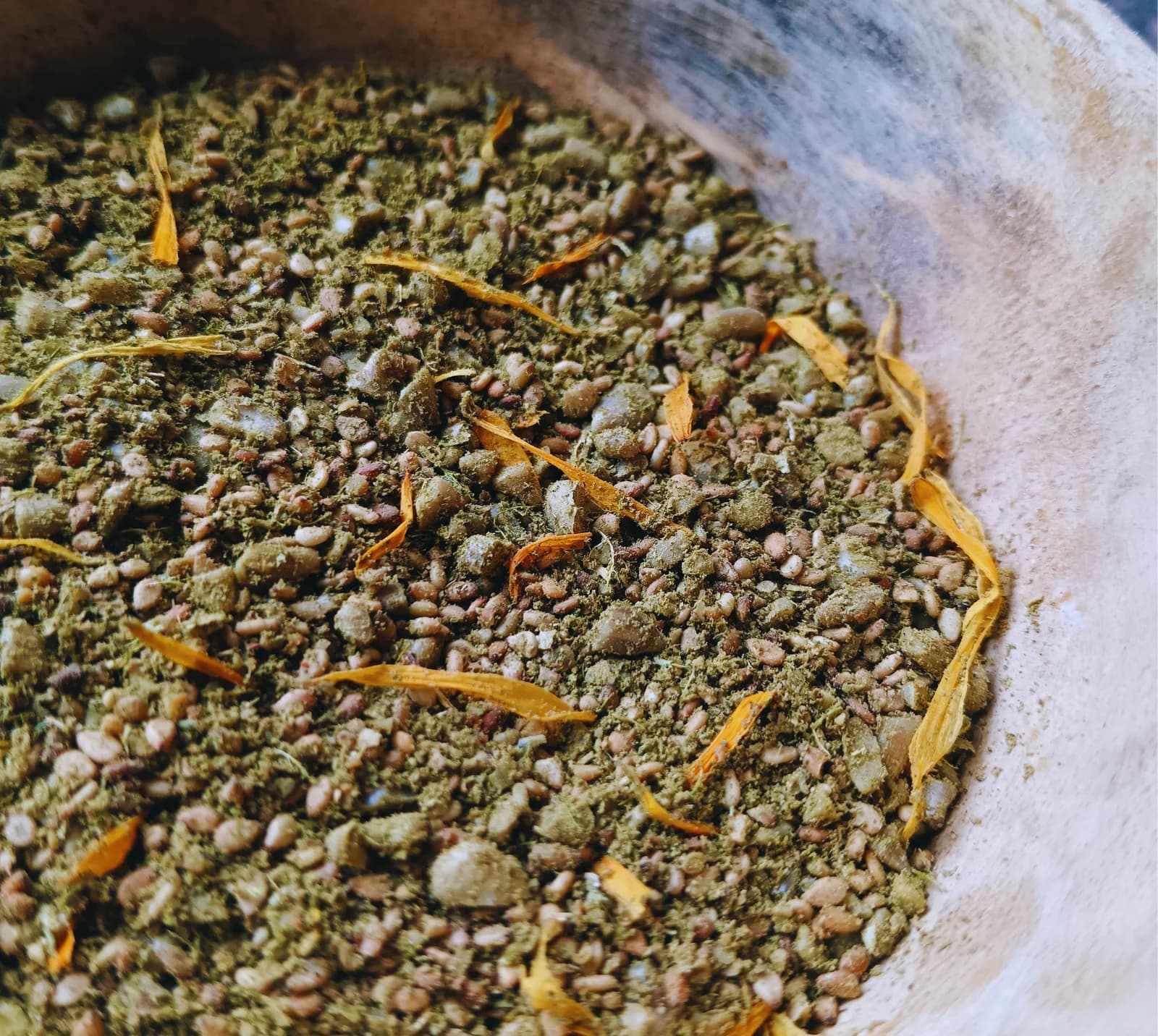 Gomasio dans un bol de bois, graines toastées et pétales de calendula